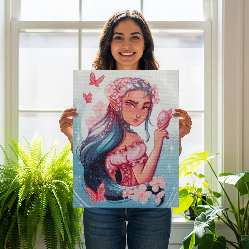 Frau hält Bild mit Diamond Painting Fee mit blauen Haaren und rosa Schmetterlingen in der Hand